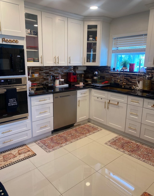 kitchen with light tile patterned flooring, sink, white cabinetry, stainless steel appliances, and backsplash