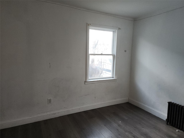 spare room featuring dark wood-type flooring and radiator heating unit