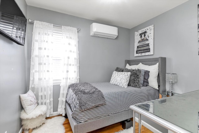 bedroom with multiple windows, wood-type flooring, and a wall unit AC