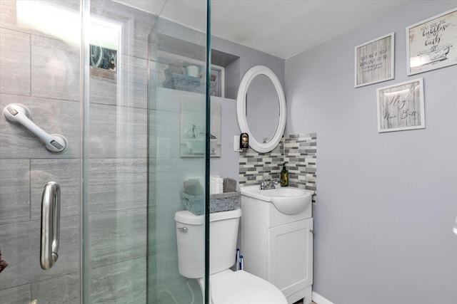 bathroom with a shower with door, vanity, backsplash, and toilet