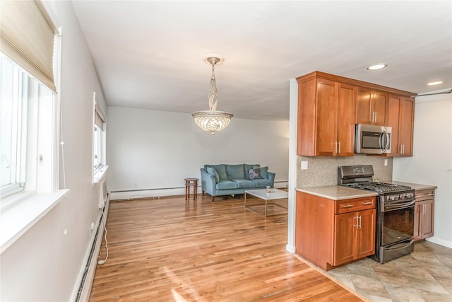 kitchen featuring pendant lighting, decorative backsplash, light hardwood / wood-style flooring, and appliances with stainless steel finishes