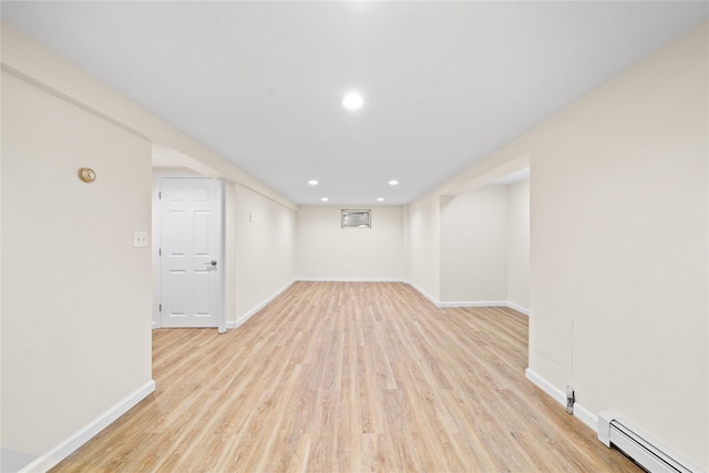 basement with a baseboard heating unit and light hardwood / wood-style floors