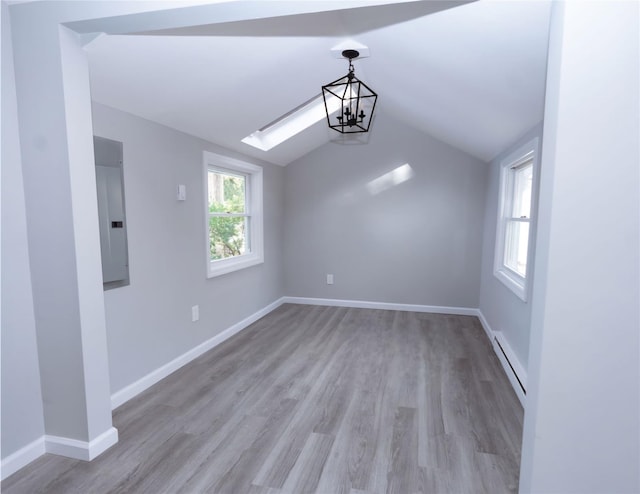 unfurnished dining area featuring a healthy amount of sunlight, lofted ceiling with skylight, electric panel, and baseboard heating