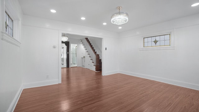 spare room featuring wood-type flooring and a chandelier