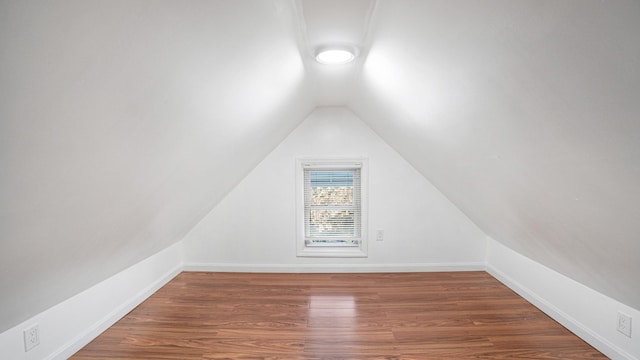 additional living space with dark wood-type flooring and vaulted ceiling