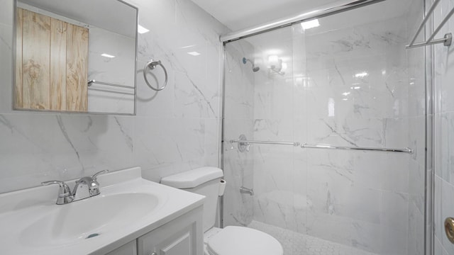 bathroom featuring walk in shower, vanity, toilet, and tile walls