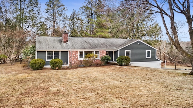 view of front facade featuring brick siding, a front yard, and a chimney