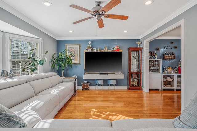 living room with hardwood / wood-style flooring, ornamental molding, indoor bar, and ceiling fan