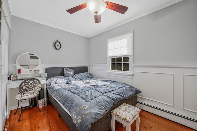 bedroom with crown molding, hardwood / wood-style flooring, ceiling fan, and baseboard heating