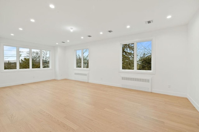 unfurnished room with radiator heating unit and light wood-type flooring