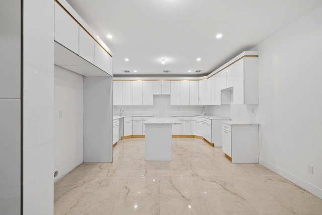 kitchen featuring white cabinetry, a center island, and sink