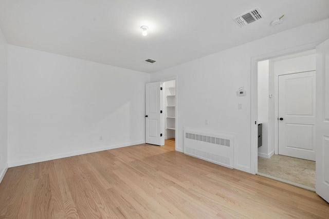 interior space with radiator heating unit and light hardwood / wood-style floors