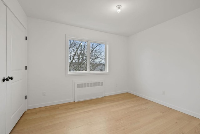 empty room featuring radiator heating unit and light hardwood / wood-style flooring