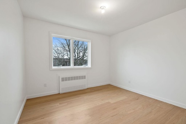 unfurnished room with radiator heating unit and light wood-type flooring