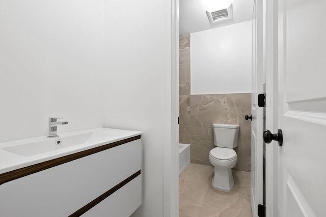 full bathroom with vanity, toilet, shower / washtub combination, and tile walls