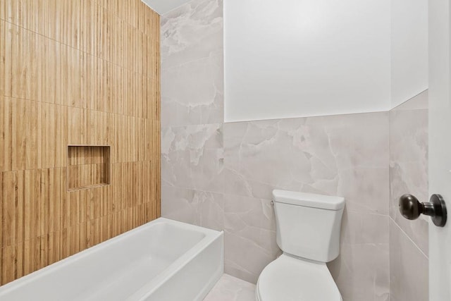 bathroom featuring toilet, a bath, and tile walls