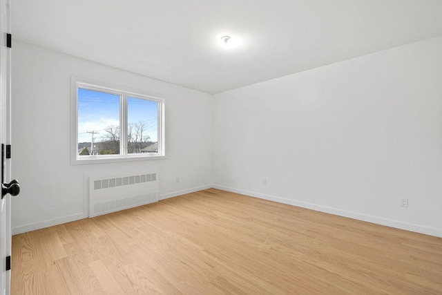 spare room with radiator and light wood-type flooring