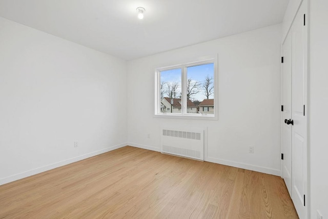 spare room with radiator heating unit and light wood-type flooring