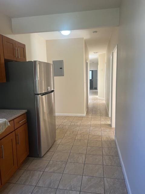 kitchen featuring stainless steel refrigerator, electric panel, and light tile patterned flooring