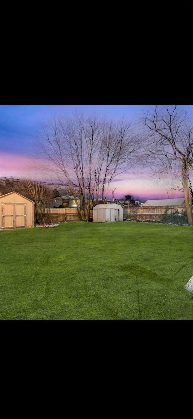 yard at dusk featuring a storage unit