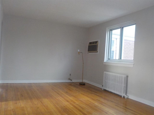 empty room with radiator, a wall mounted AC, and light wood-type flooring