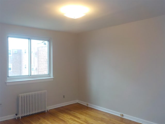 empty room featuring radiator heating unit and light wood-type flooring