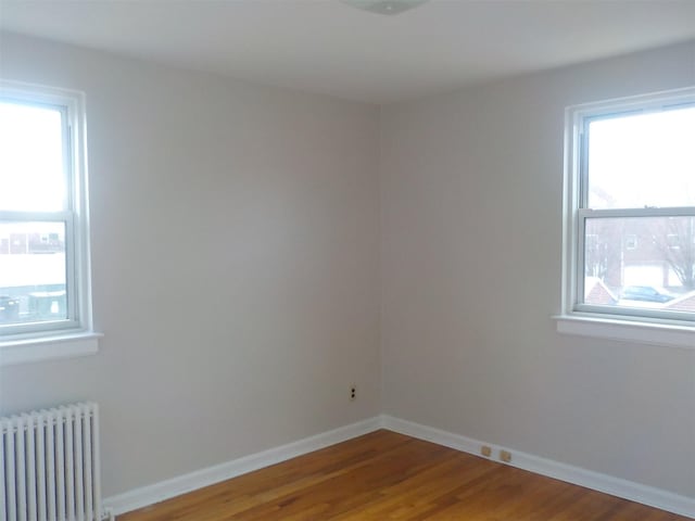 spare room featuring radiator and hardwood / wood-style floors