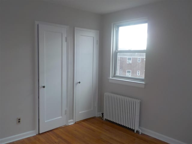 interior space with hardwood / wood-style floors and radiator heating unit