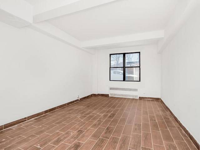 empty room featuring beamed ceiling and radiator