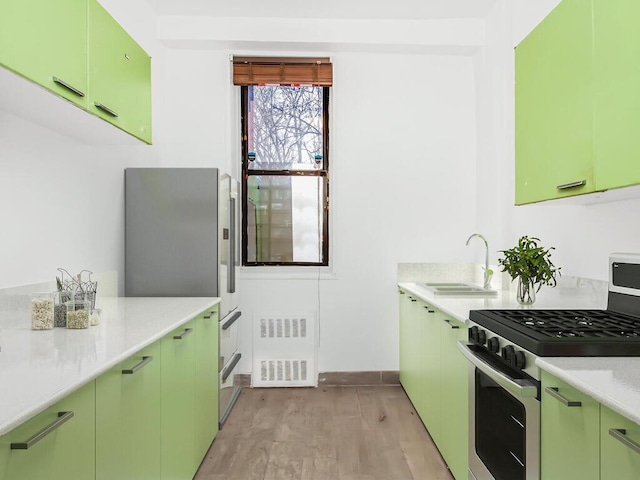 kitchen featuring sink, stainless steel appliances, light hardwood / wood-style floors, and green cabinetry