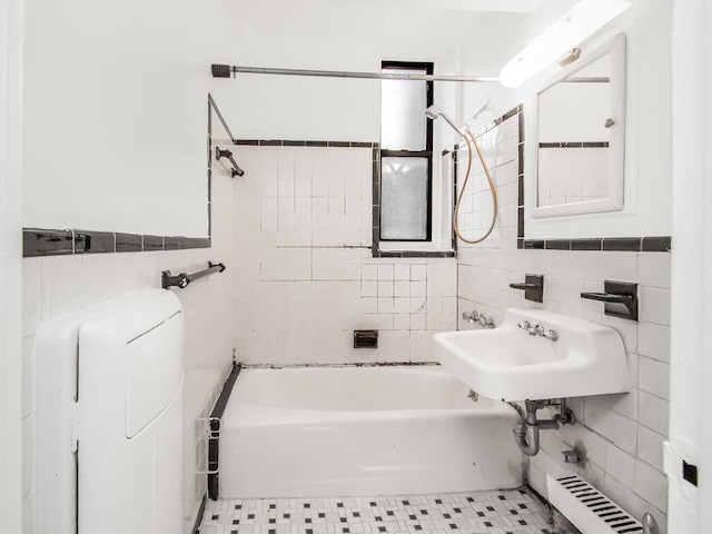 bathroom featuring tile walls, sink, tiled shower / bath combo, and radiator heating unit