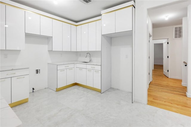 kitchen featuring white cabinetry and sink