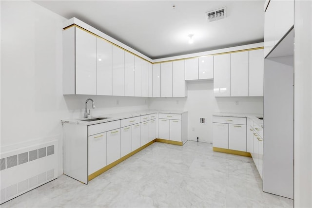 kitchen with white cabinetry, radiator, and sink