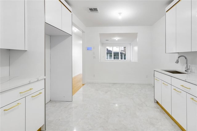 kitchen featuring white cabinetry, sink, and light stone counters