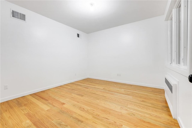 unfurnished room featuring radiator heating unit and light wood-type flooring