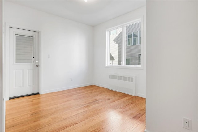 spare room featuring radiator and light hardwood / wood-style flooring