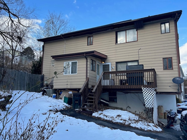 snow covered rear of property with a deck