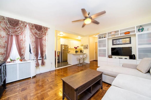 living room with radiator, built in shelves, parquet floors, and ceiling fan