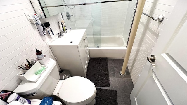 full bathroom featuring tile walls, bath / shower combo with glass door, vanity, tasteful backsplash, and toilet