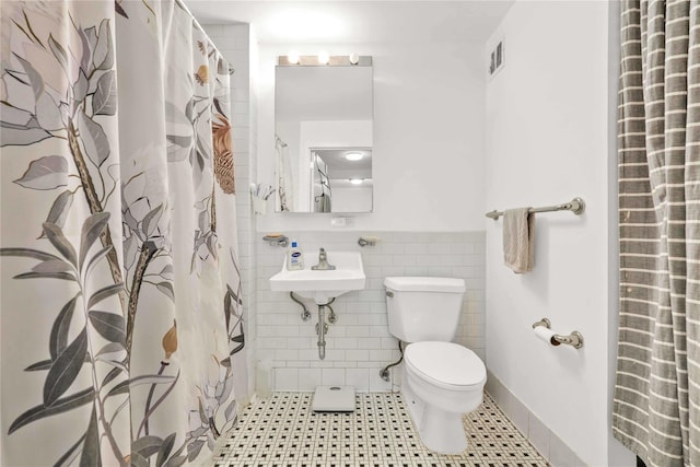 bathroom with toilet, tile walls, tile patterned floors, and walk in shower