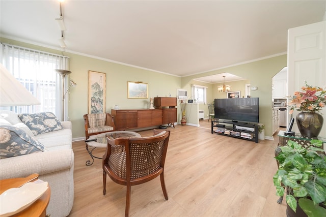 living room featuring an inviting chandelier, crown molding, track lighting, and light wood-type flooring