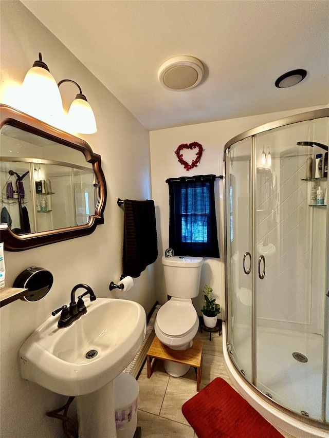 bathroom featuring sink, toilet, and a shower with door