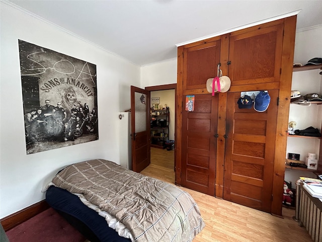 bedroom featuring ornamental molding and light wood-type flooring