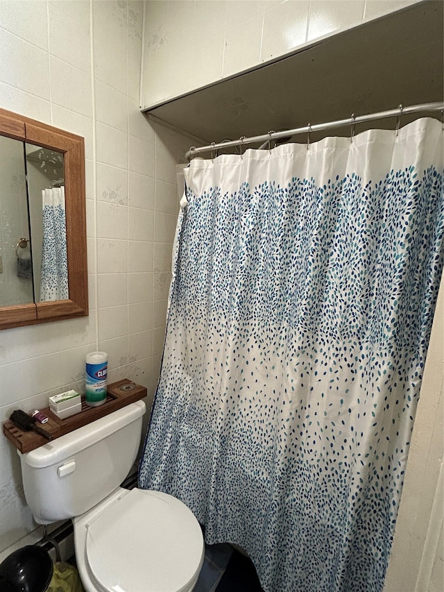 bathroom featuring tile walls, toilet, and a shower with shower curtain