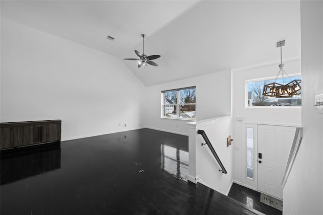 foyer with lofted ceiling, ceiling fan with notable chandelier, and dark wood-type flooring