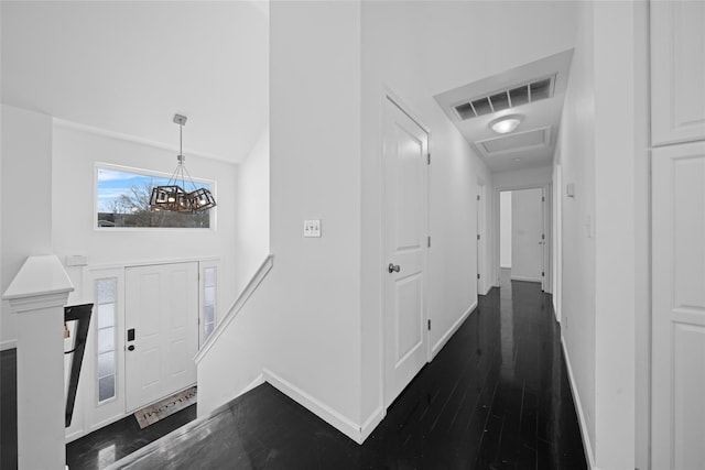 foyer entrance with dark wood-type flooring, an inviting chandelier, and a high ceiling