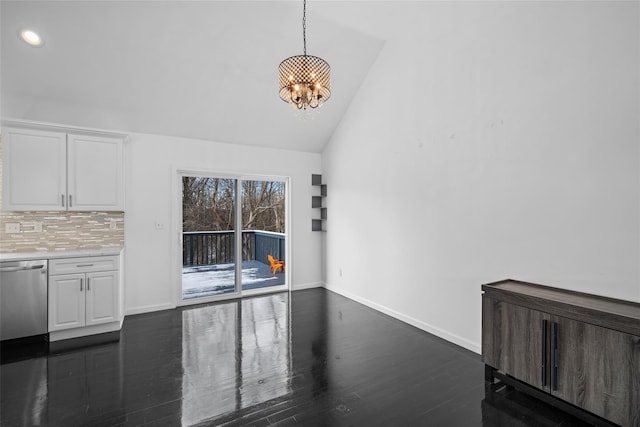 unfurnished dining area with dark wood-type flooring, an inviting chandelier, and vaulted ceiling