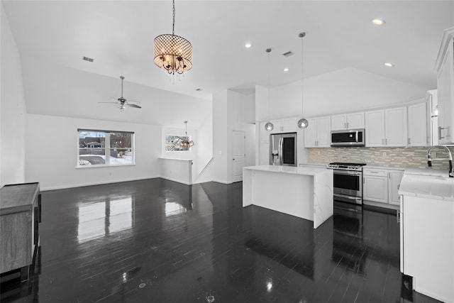 kitchen with appliances with stainless steel finishes, pendant lighting, white cabinetry, sink, and a center island