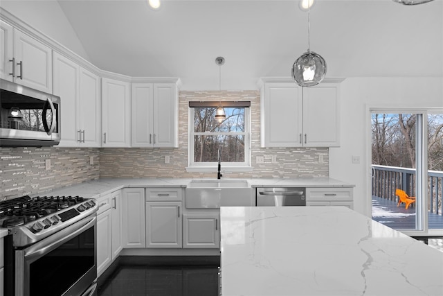 kitchen with sink, decorative light fixtures, appliances with stainless steel finishes, light stone countertops, and white cabinets