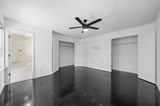 unfurnished bedroom featuring ceiling fan, connected bathroom, two closets, and dark hardwood / wood-style flooring